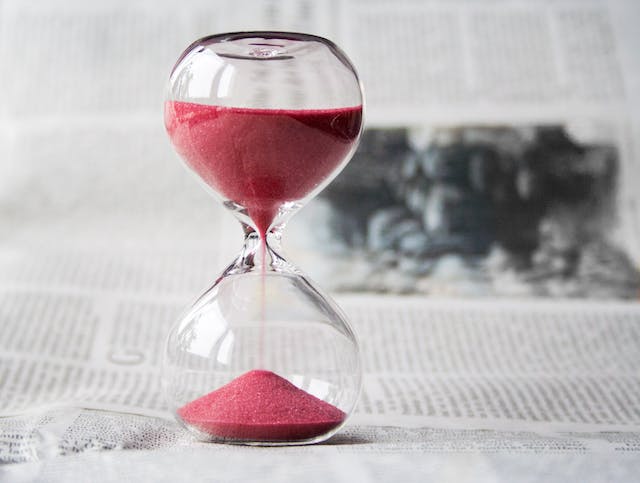 An hourglass with red sand flowing down.