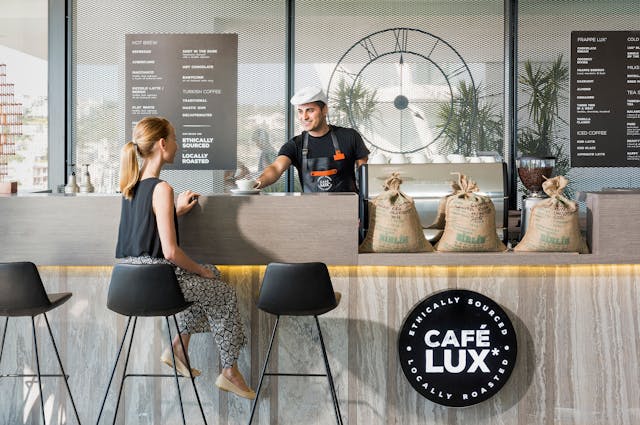 Um barista a servir um cliente num café recentemente inaugurado.