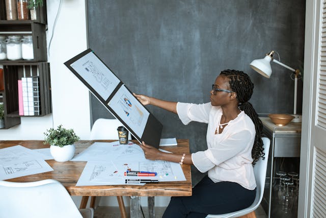 A woman in a white shirt is looking at schematics and infographics. 