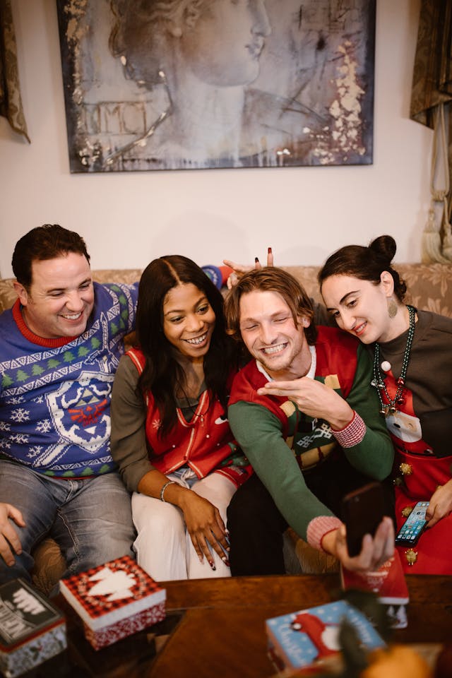 A group of friends wearing comfy Christmas sweaters taking a selfie.