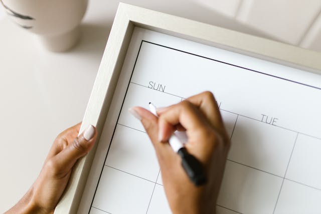 Qualcuno scrive su un calendario alla lavagna con un pennarello.