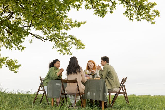 Een groep vrienden die discussiëren tijdens een maaltijd in een tuin.
