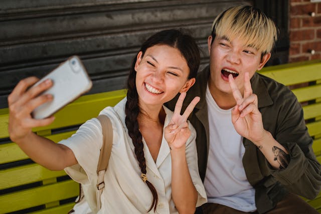 Un couple brandissant des signes de paix avec leurs doigts tout en prenant un selfie.