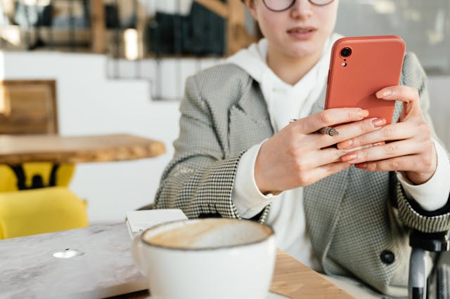 ペンを持ちながら携帯電話をスクロールする女性。