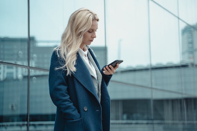 Een vrouw staat met haar telefoon.