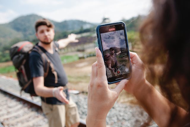 A woman taking a vertical video of her companion during a hike.