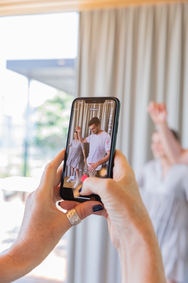 Een vrouw neemt een video op van een dansende man en vrouw. 