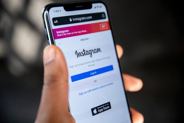 A person holding a phone with an Instagram login page open. 