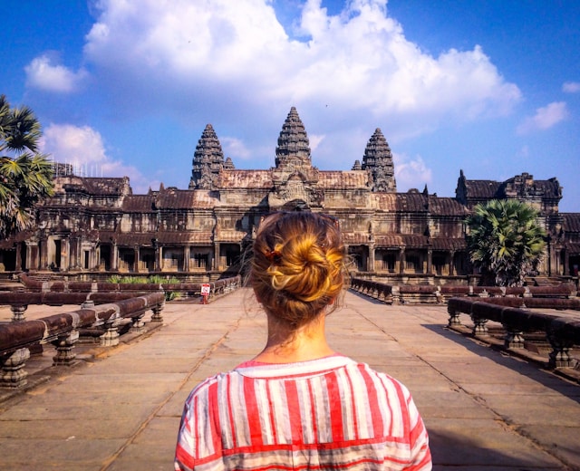 Het achteraanzicht van een vrouwelijke travel influencer tegenover de majestueuze Angkor Wat in Cambodja.