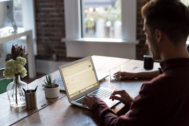 A man is typing on a laptop. 