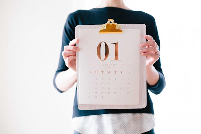 A woman holding up a monthly calendar.