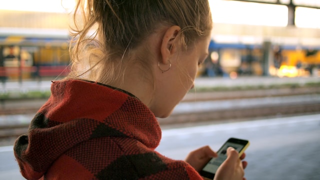 Une femme qui marche en lisant un message sur son smartphone.