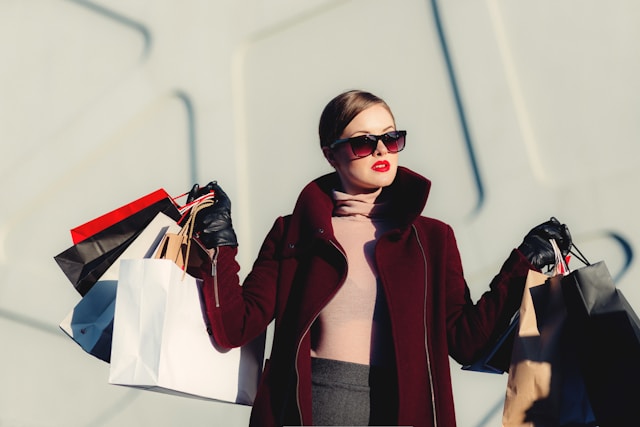 A sophisticated woman holding many shopping bags in both hands.