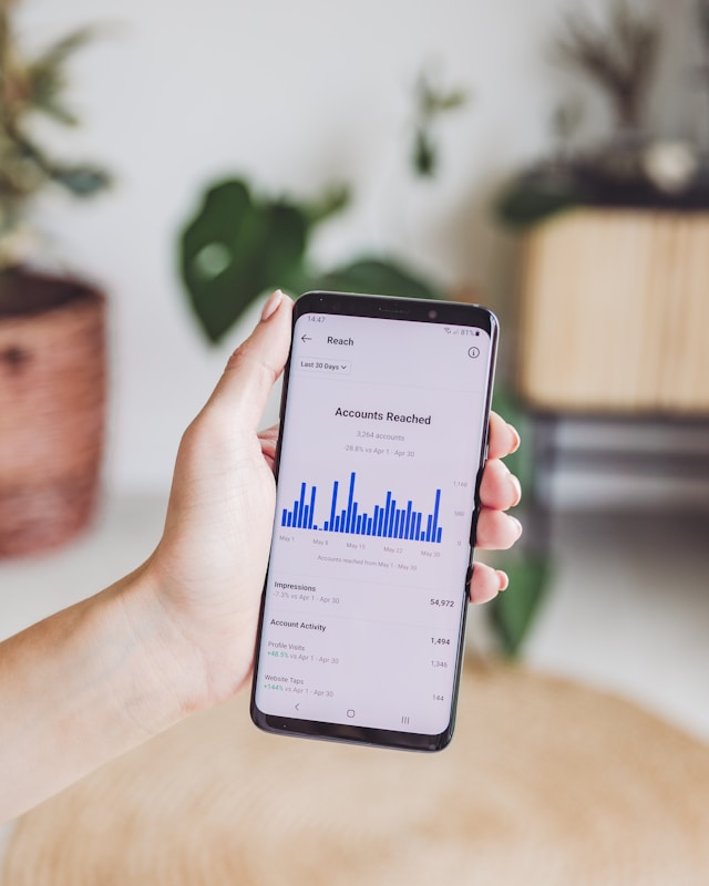 georgia-de-lotz-Ebb8fe-NZtM-unsplash-1 | Path Social Quelqu'un brandit un téléphone affichant le nombre de comptes atteints sur Insights pour un compte Instagram .