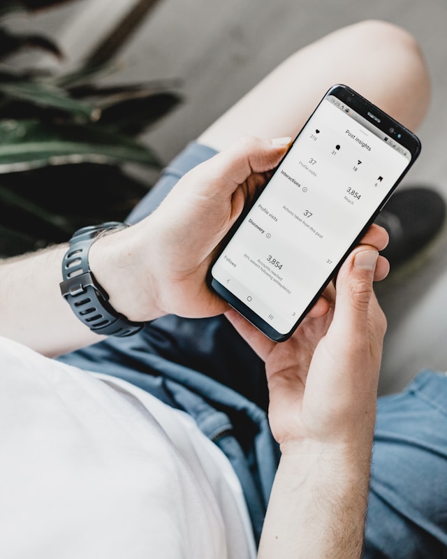 A man holding a phone displaying his account’s Instagram Insights dashboard.