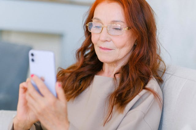 Een vrouw met rood haar die een mobiele telefoon gebruikt. 