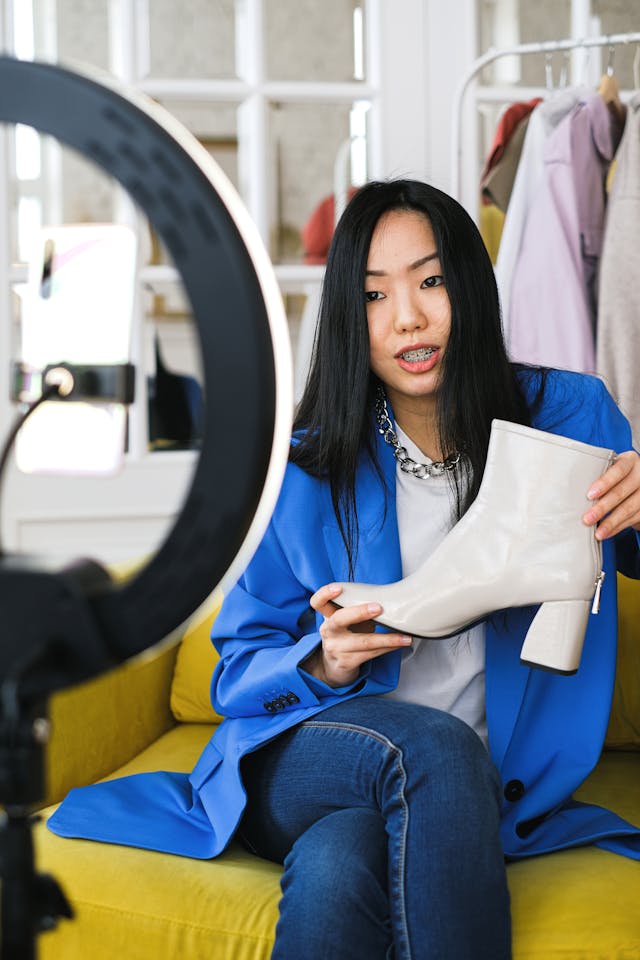 A woman recording a video of herself talking while showing a boot.