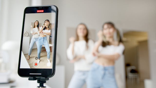 Two young female influencers recording a dance challenge video for social media.