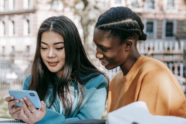 Deux femmes regardent quelque chose ensemble sur un téléphone.