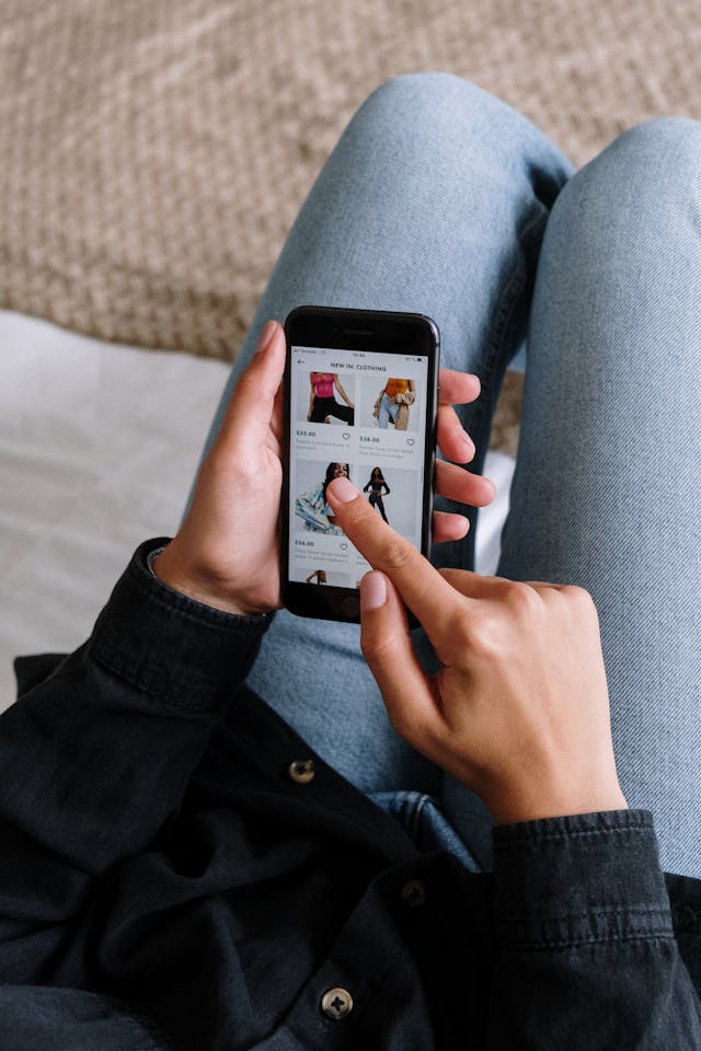 A person looking through a phone with a catalog of clothing products.