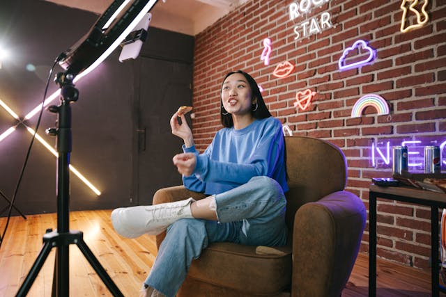 A female influencer smiling while talking in front of her smartphone and ring light.