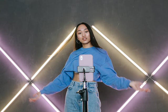 A young woman filming a dance challenge using her phone on a tripod.