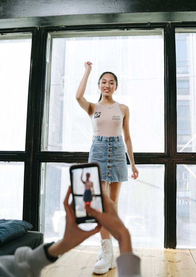 Uma jovem a ser filmada por alguém enquanto faz um desafio de dança nas redes sociais.