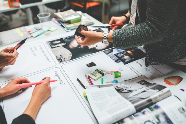 A group of people working together with pens and papers. 