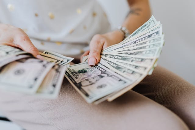 Iemand houdt een waaier met knisperende Amerikaanse dollarbiljetten vast.