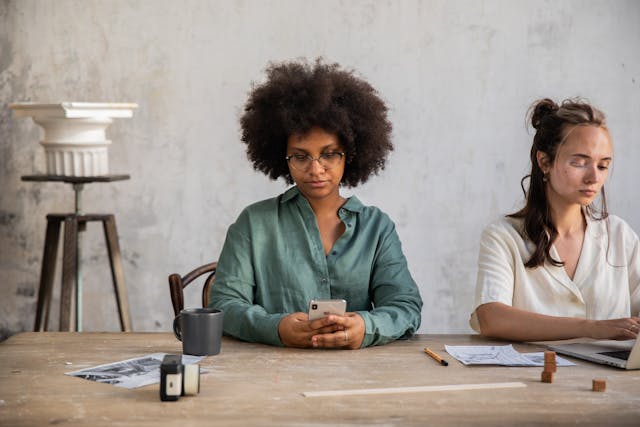 Duas mulheres a utilizar os seus telemóveis. 