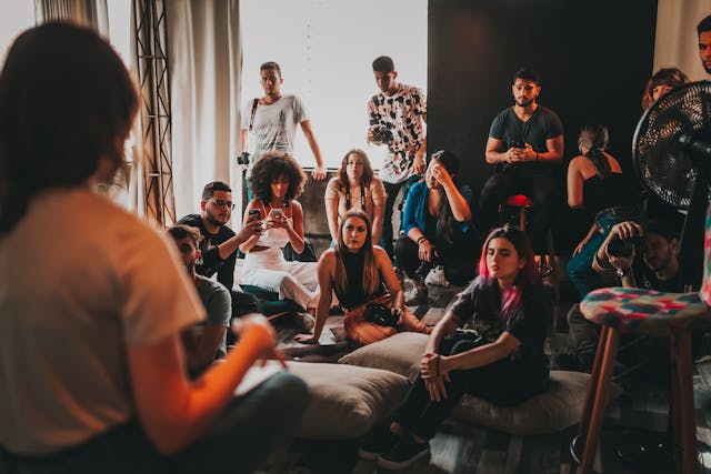 Een groep jongeren luistert naar een spreker vooraan in de zaal.