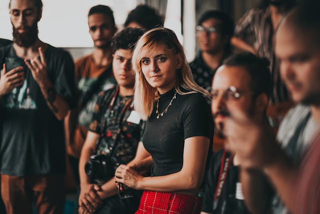 Uma mulher na plateia de uma conferência a ouvir alguém falar.