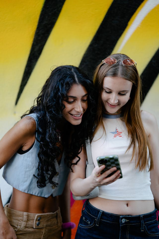 Twee tienermeisjes kijken samen naar een telefoon.