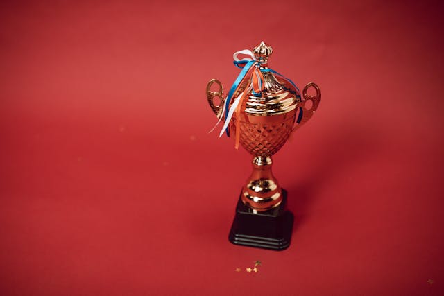 Un trofeu cu panglici pe un fundal roșu.