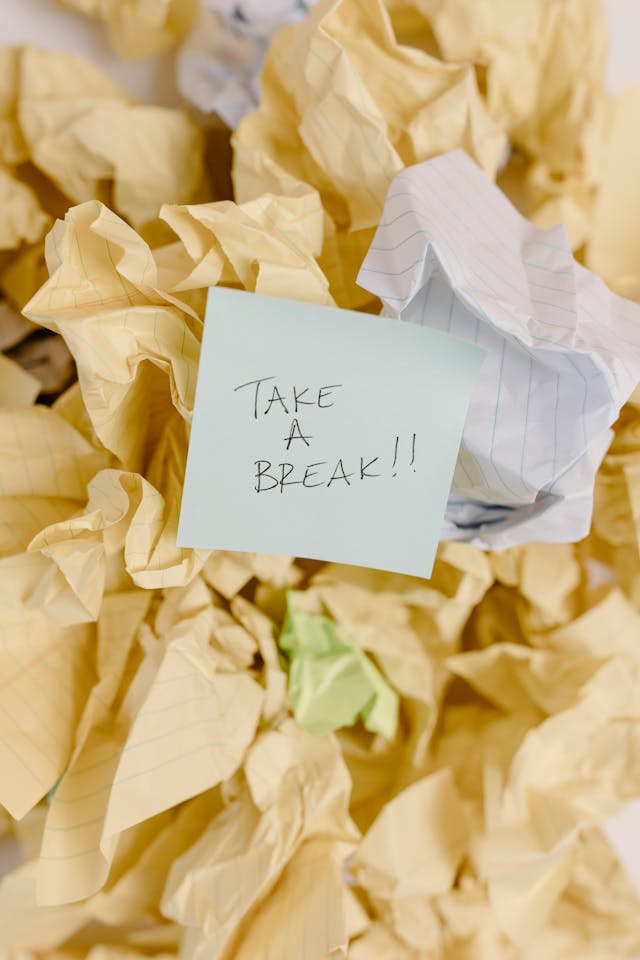 Un foglio di carta con su scritto "Fai una pausa!" circondato da altri fogli accartocciati.