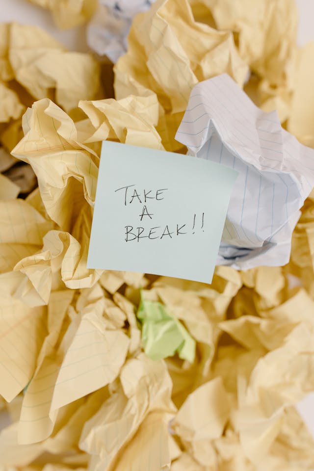 Ein Stück Papier mit der Aufschrift "Mach mal Pause!", umgeben von anderen zerknitterten Papieren.