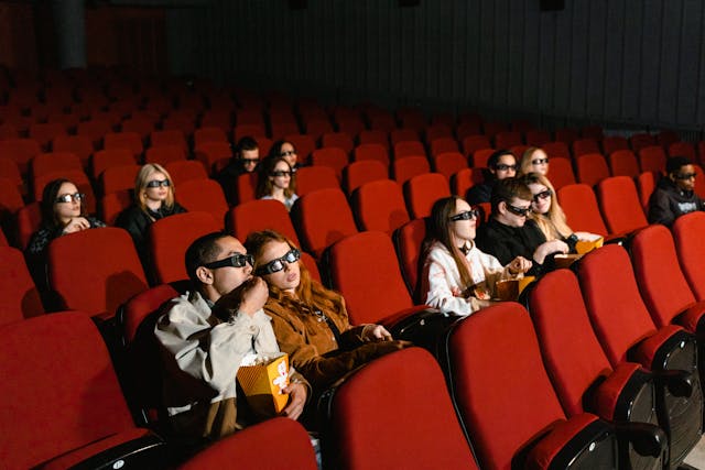 영화관에서 빨간 의자에 앉아 영화를 상영하는 관객.