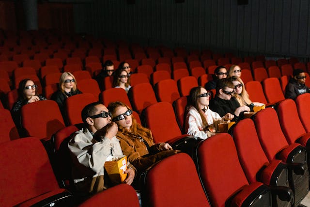 A movie screening audience sitting on red chairs at the cinema.