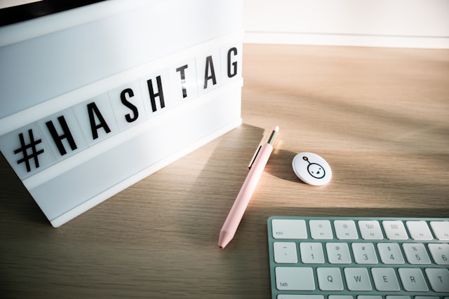 A letterboard that says “#HASHTAG” next to a pen, mouse, and keyboard.