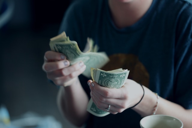 Someone counting dollar bills in their hands.