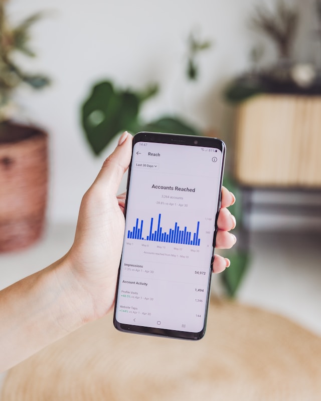 Iemand die een telefoon vasthoudt en de metriek "bereikte accounts" weergeeft op Instagram Insights.