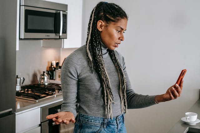 A woman looking at her phone with a frustrated facial expression.