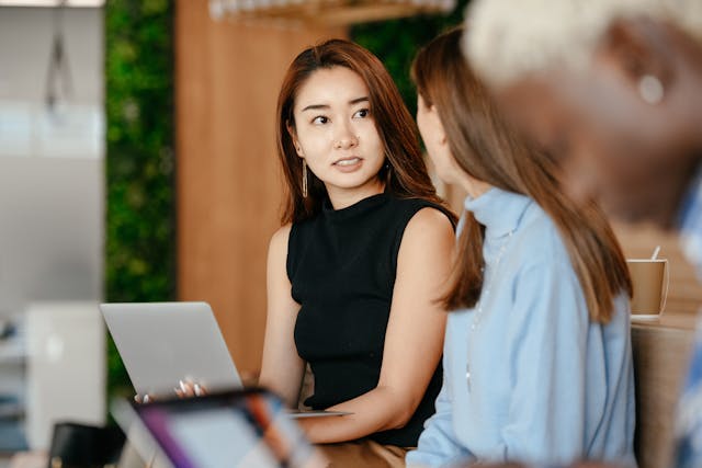 A woman looking at colleagues while holding her laptop.