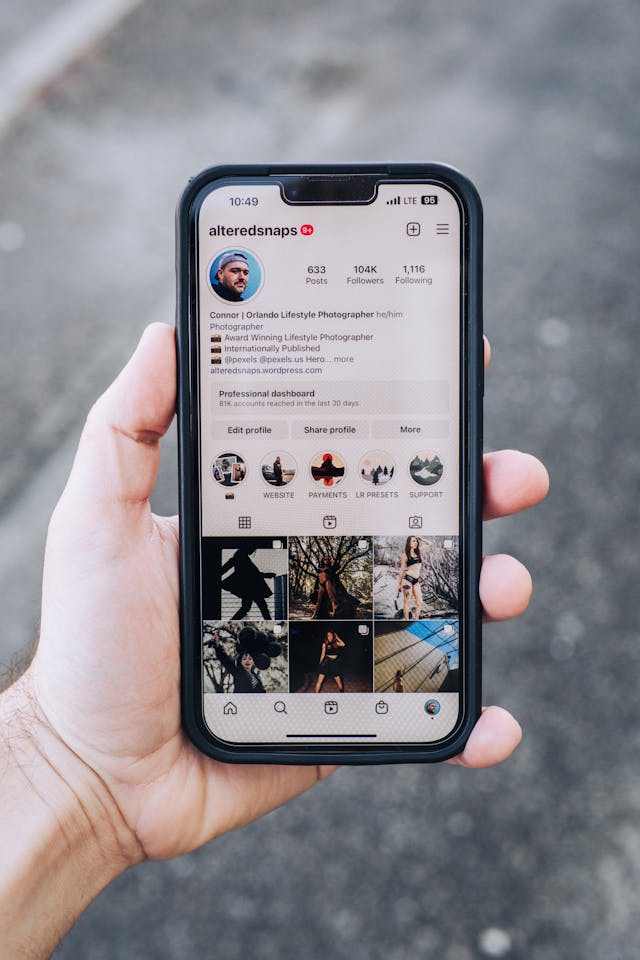 Iemand met een telefoon waarop het Instagram profiel en de gedetailleerde biografie van een man staan.