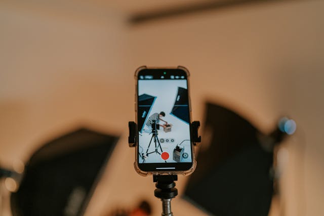 Someone recording a vertical video on a smartphone on a tripod at a production set.