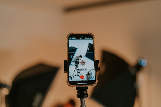 Alguien graba un vídeo vertical con un smartphone sobre un trípode en un plató de producción.