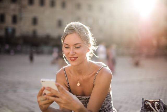 Uma rapariga a sorrir enquanto vê vídeos no seu telemóvel.