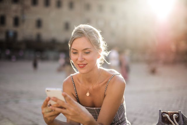 Una ragazza che sorride mentre guarda dei video sul suo telefono.