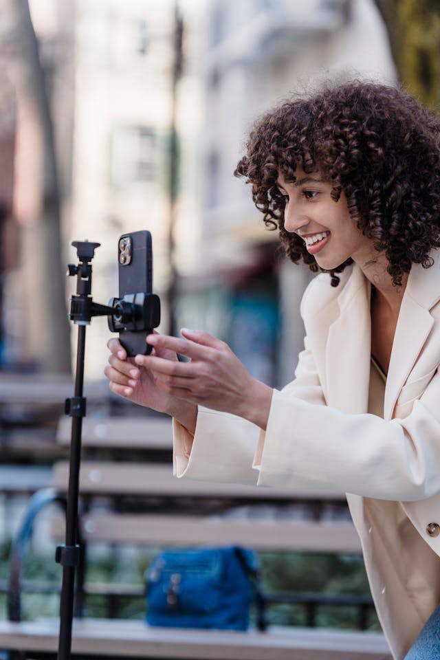 A female content creator setting up her phone and tripod to film video content.