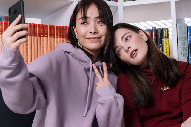 Two teenage girls taking a selfie in a library.